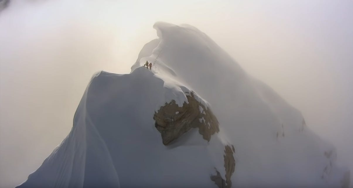 Two small figures on misty snow ridge