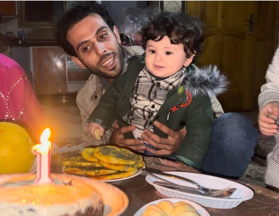 Tareq Hajjaj and his son Qais on his first birthday, in an abandoned home in Yibna refugee camp, December 2023. (Photo: Tareq Hajjaj)
