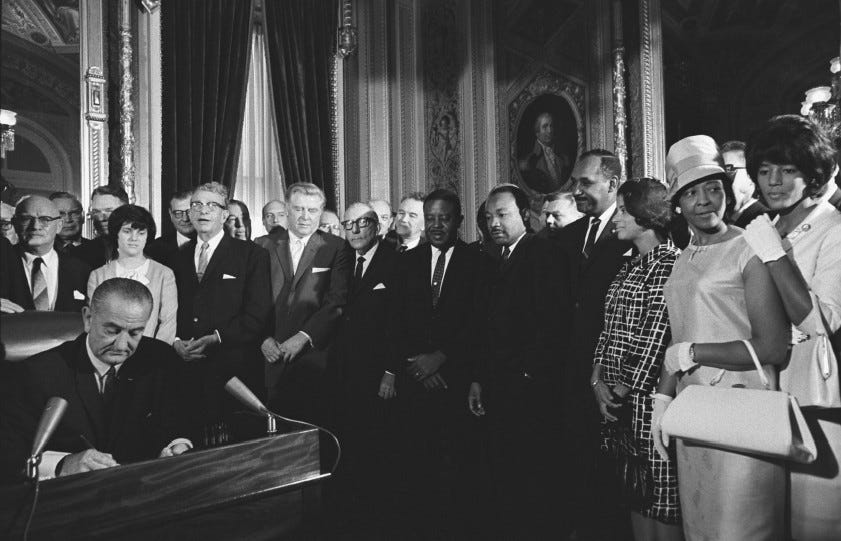 President Lyndon Johnson signing the Voting Rights Act in August 1965 as Martin Luther King, Jr., and other civil rights leaders look on.  (National Archives)