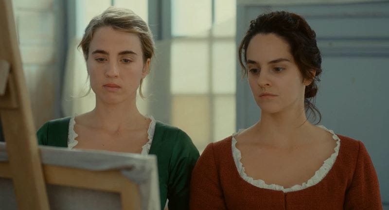 two women, one blonde and one brunette, are standing shoulder to shoulder looking at a painting on an easel together. two women, one blonde and one brunette, are standing shoulder to shoulder looking at a painting on an easel together.