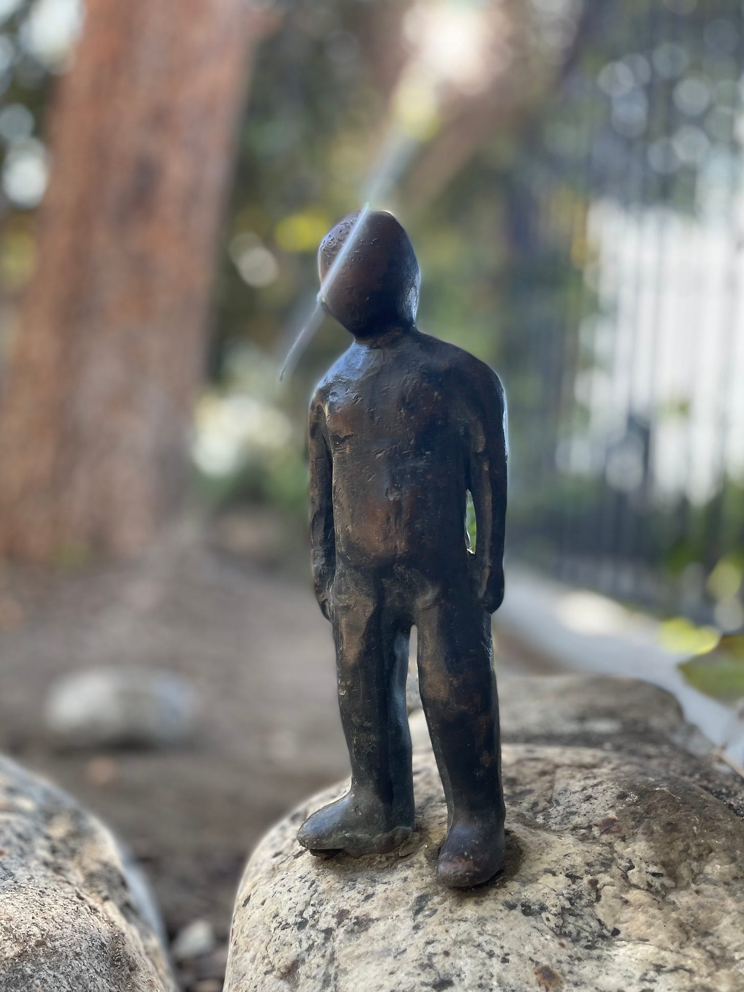 small iron sculpture of a man with a ray of sunlight passing just over his head