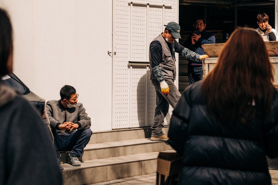 Men stand around on a work break with a woman walking by. Men stand around on a work break with a woman walking by.