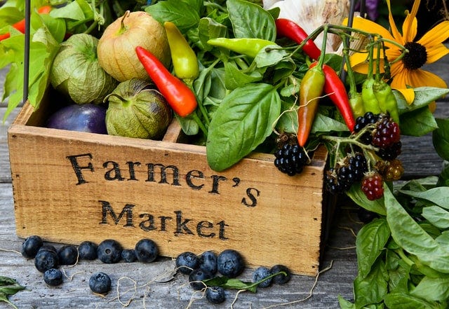 A box of harvested vegetables displayed at a farmers' market.