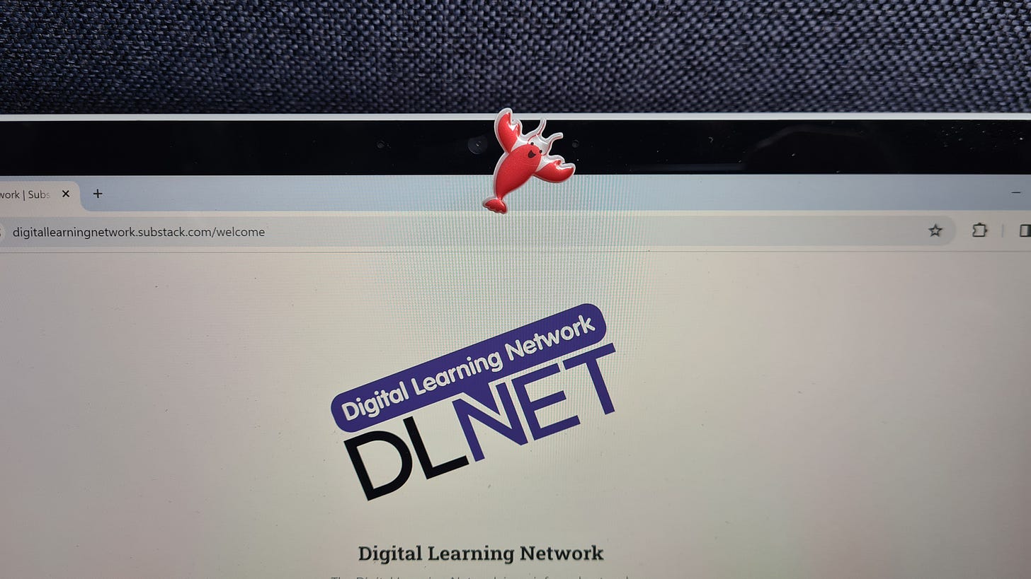 A laptop screen that has a sticker of a lobster stuck next to the webcam.