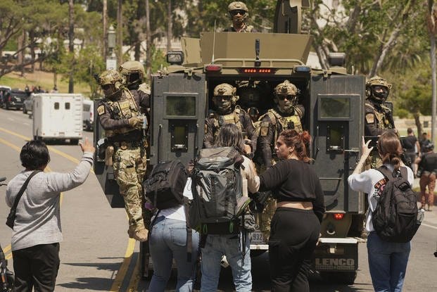 Federal agents ride on an armored vehicle at MacArthur Park Monday, July 7, 2025, in Los Angeles. (AP Photo/Damian Dovarganes) Federal agents ride on an armored vehicle in Los Angeles.