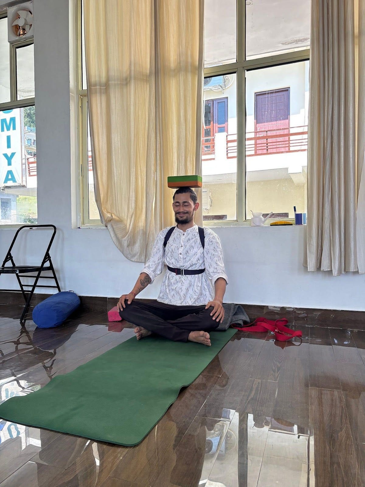 A person sitting on a yoga mat with a stack of boxes on his head
Description automatically generated A person sitting on a yoga mat with a stack of boxes on his head
Description automatically generated