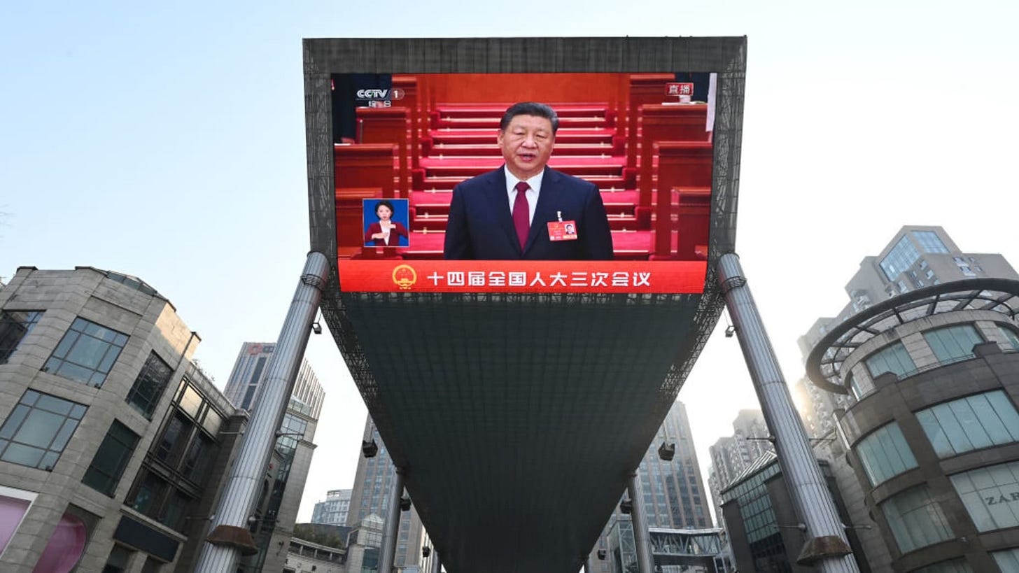 TOPSHOT - This photo shows a general view of a screen broadcasting live footage of China's President Xi Jinping attending the opening session of the National People's Congress (NPC) as seen outside a shopping mall in Beijing on March 5, 2025. (Photo by GREG BAKER / AFP) (Photo by GREG BAKER/AFP via Getty Images)          