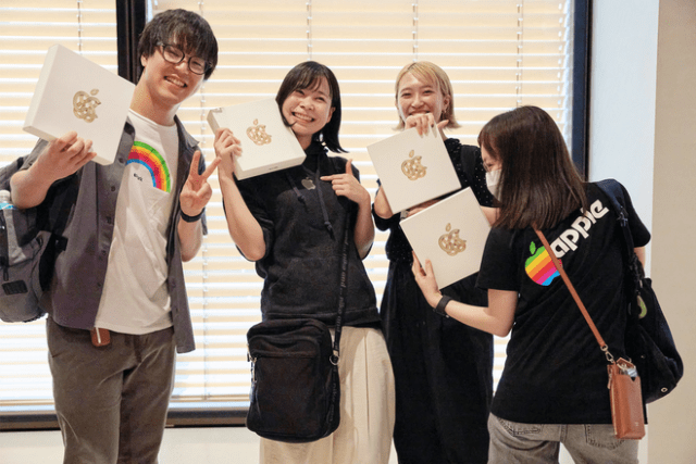 Guests of the store’s reopening show off their commemorative gift boxes, which include a tote bag and pin inside.