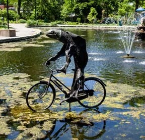 statue of a fish on a bicycle
