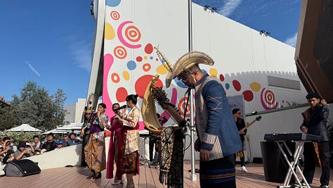 A collage of six photos from the Osaka World Expo 2025. Top left: a giant white Gundam robot statue set against a blue sky. Top middle: people exploring a dimly lit exhibit with a statue in traditional Southeast Asian attire and rice stalks on display. Top right: performers dressed in colorful cultural costumes on an outdoor stage with a bright patterned backdrop. Bottom left: a vast wooden pavilion with tall beams and people walking through. Bottom middle: an illuminated modern installation at night featuring mirrored structures with glowing circular displays. Bottom right: a wide view over the expo grounds at sunset, showing pavilions, pathways, and visitors.
