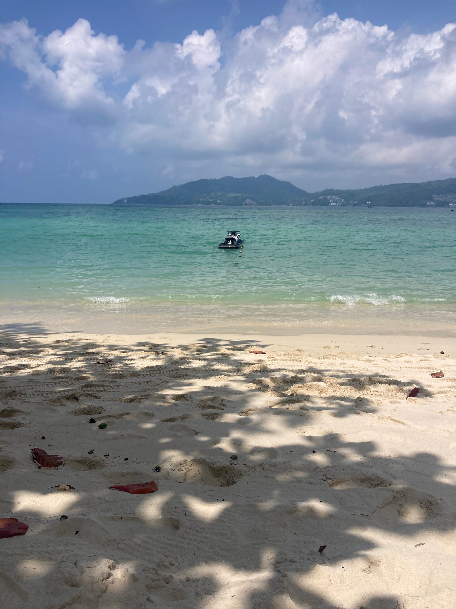 a beach in Thailand with a boat, colours vivid and clear