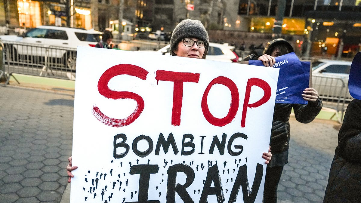 Protesters hold signs during a demonstration against U.S. military action in Iran on April 7, 2026, in New York City. (Photo by Ryan Murphy/Getty Images)