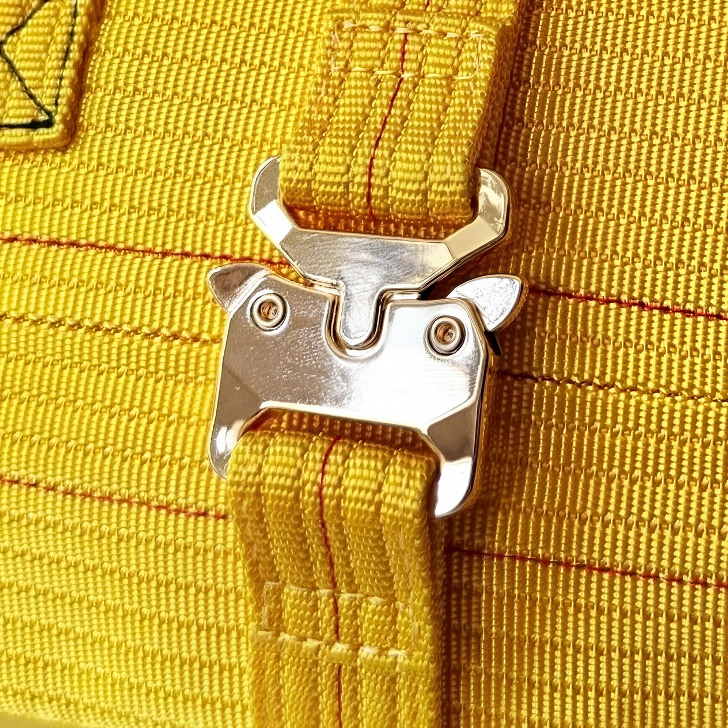 Close-up of a silver metal clasp on a yellow nylon strap bag Close-up of a silver metal clasp on a yellow nylon strap bag