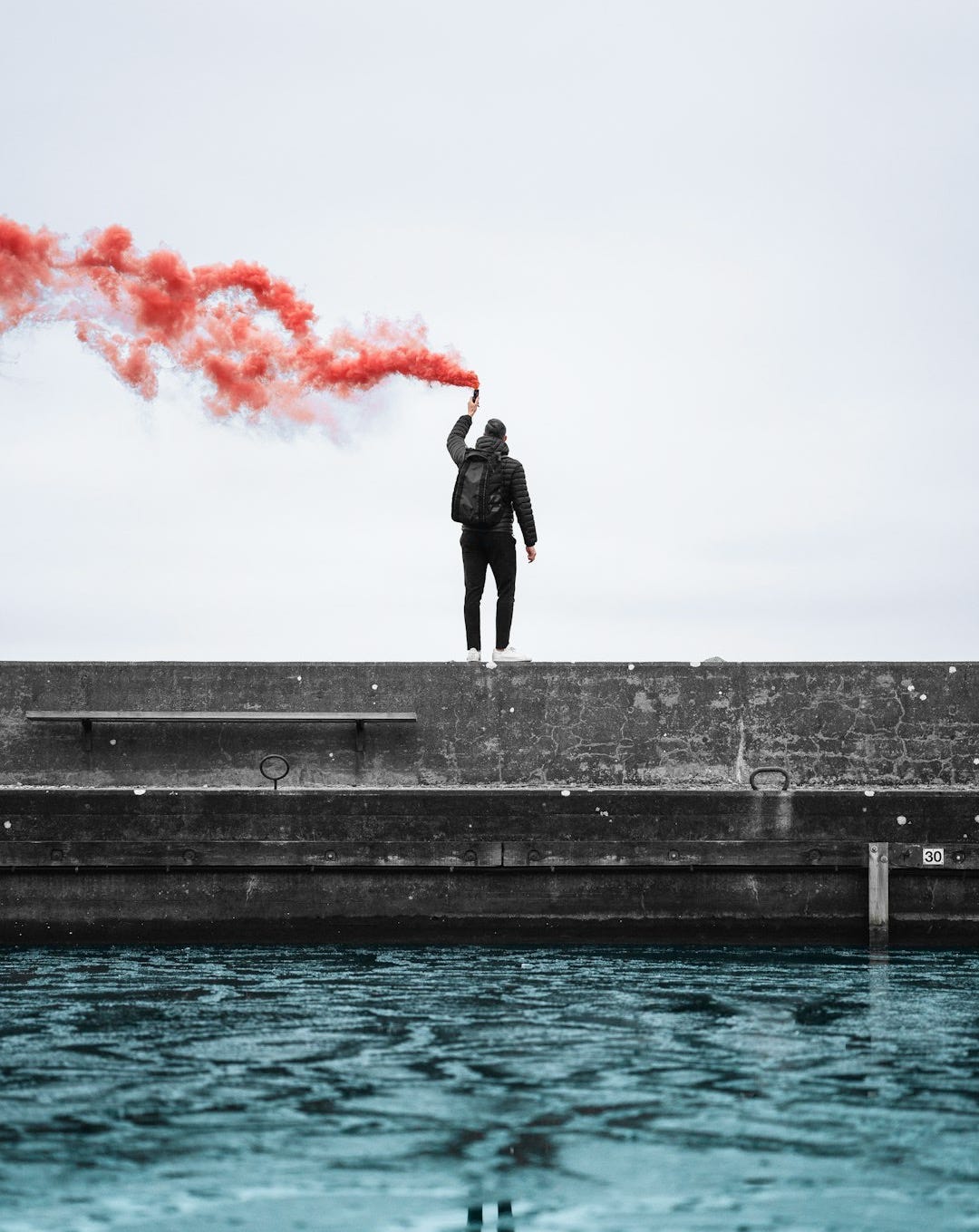 standing man holding lighted flare during daytime standing man holding lighted flare during daytime