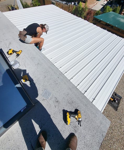Up on the ladder, roofing the patio outside my tiny house!