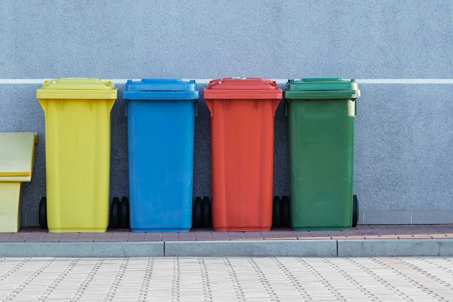 Four plastic recycling bins lined up on a curb
