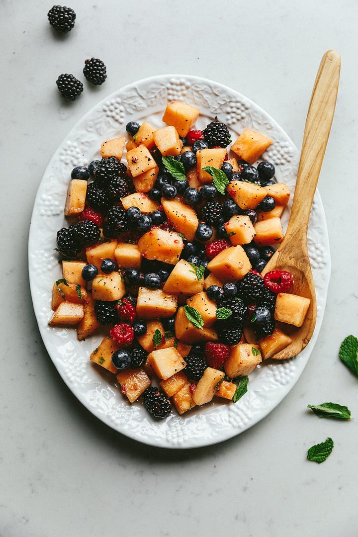 Ingredients for keto fruit salad and a fruit salad on a serving platter.
