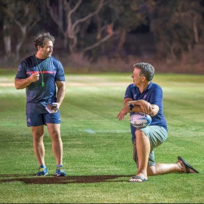 Two rugby coaches on a field