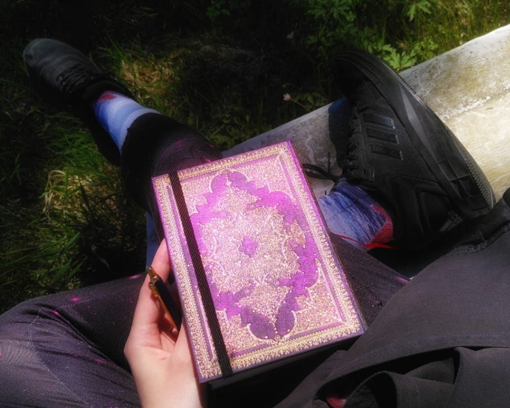 photo of me sitting on an upturned boat with a shining diary and pen in hand