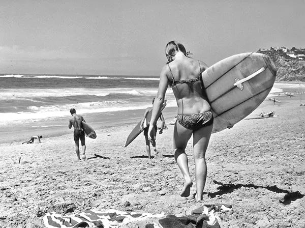 A woman carrying her surfboard down to the water on a beach near Sydney, Australia, circa 1965. A woman carrying her surfboard down to the water on a beach near Sydney, Australia, circa 1965.