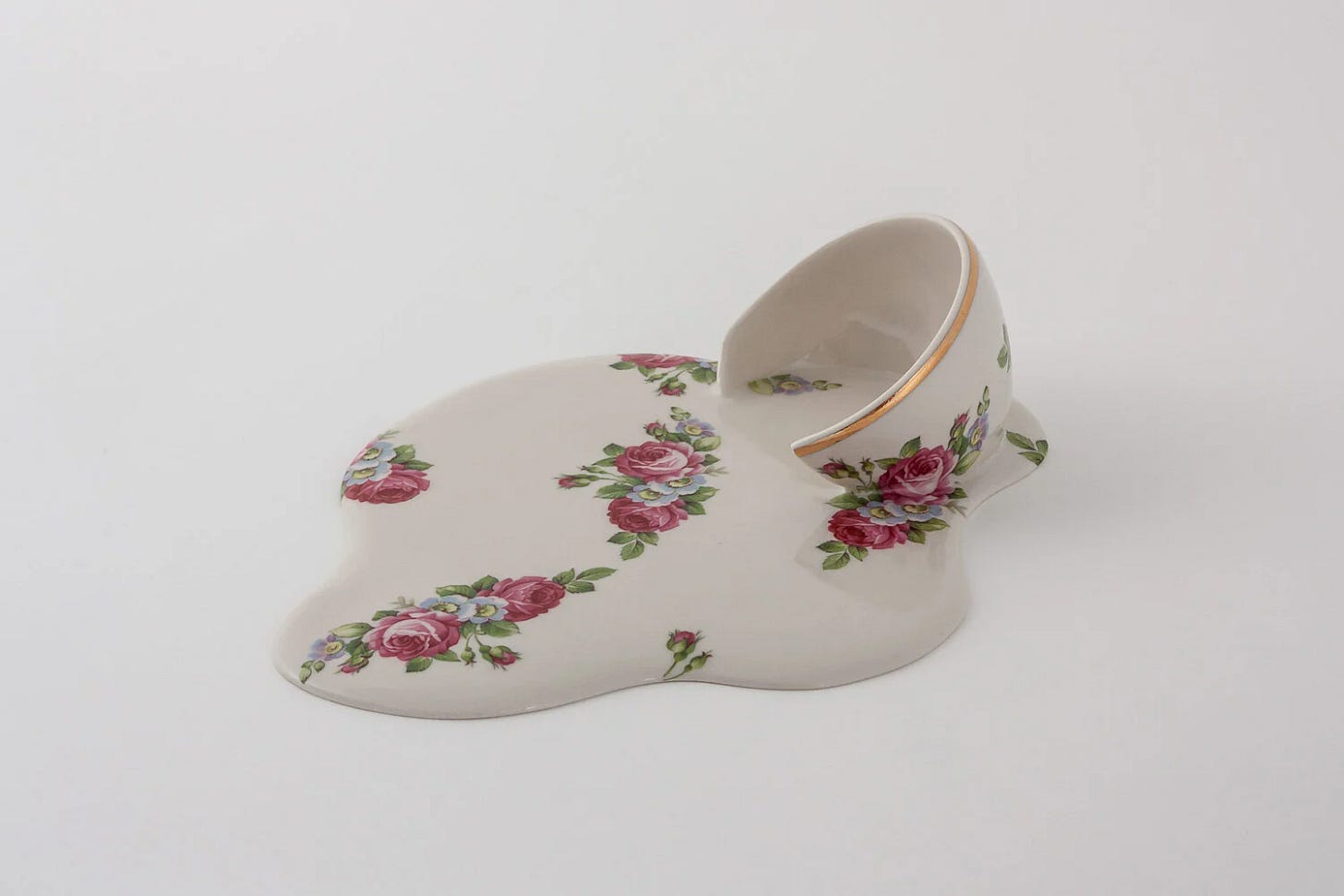 A broken, gold-rimmed teacup seems to dissolve into a porcelain puddle, across the surface of which a traditional floral motif is flowing.