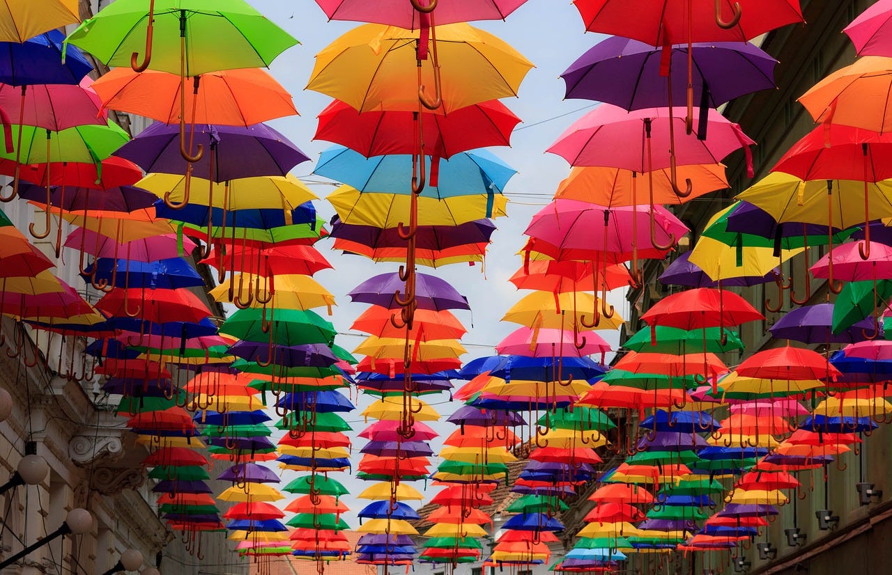 Rainbow umbrellas hanging between buildings. Image Source: Needpix.com