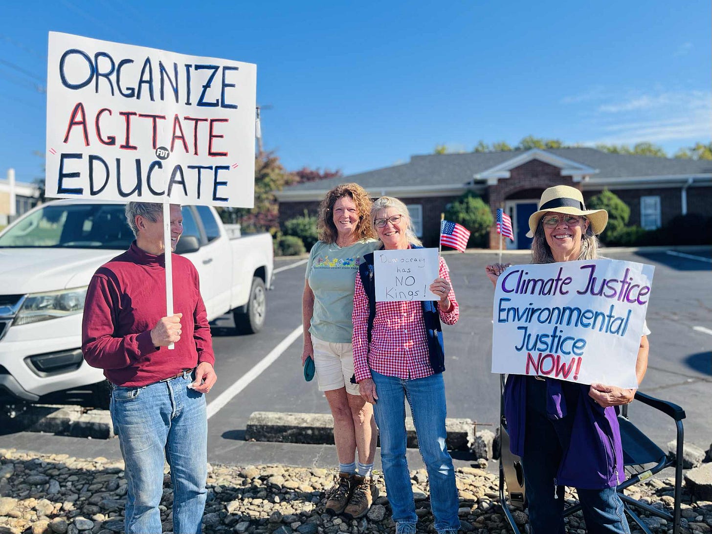 Several protestors stand with signs protesting for democracy