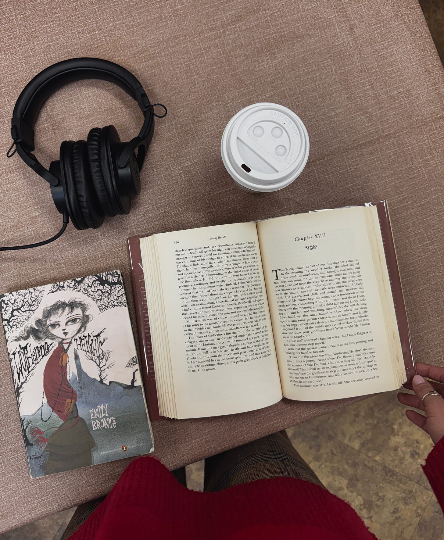 Open book on table with headphones and disposable coffee cup