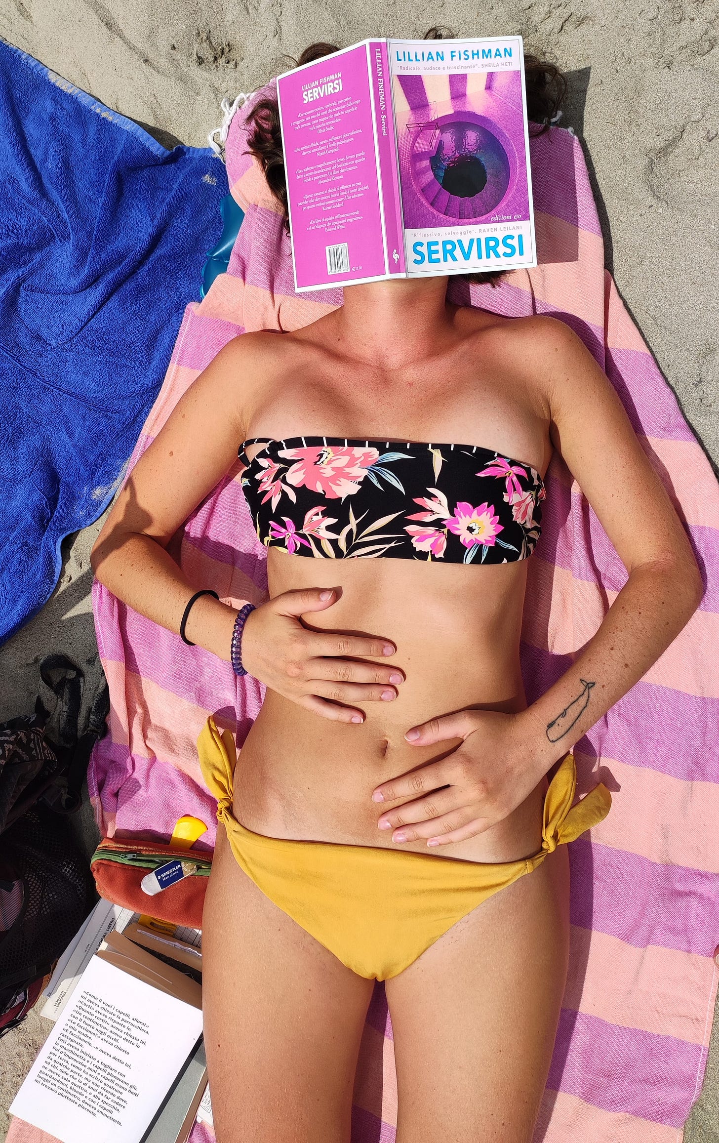Una ragazza è distesa su un telo mare, sopra una spiaggia di sabbia. Il telo mare è a righe arancioni e rosa. La ragazza, ritratta dalle ginocchia in su, indossa un costume a due pezzi. Il pezzo sotto è giallo, quello sopra con una trama a fiori. Ha le mani appoggiate sulla pancia. Un libro aperto è appoggiato sulla faccia, coprendogliela. Il libro è Sentirsi di Lillian Fishman. 