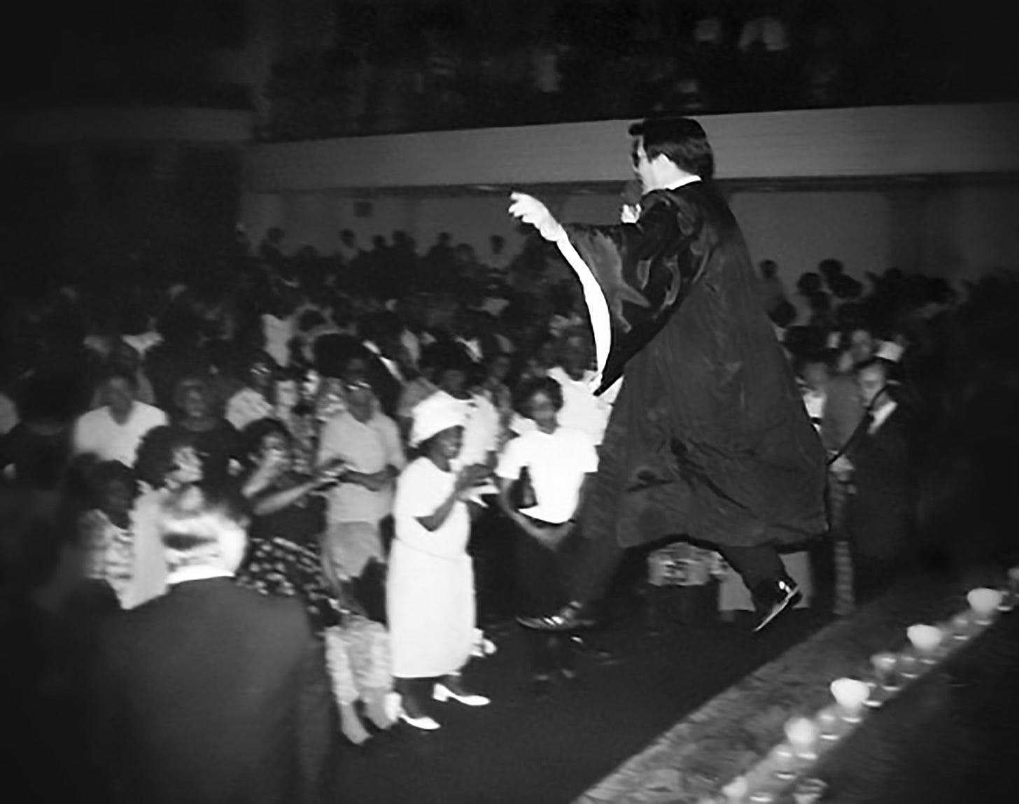 Jim Jones leaping off the stage as he preaches to a mixed-race crowd at the People's Temple
