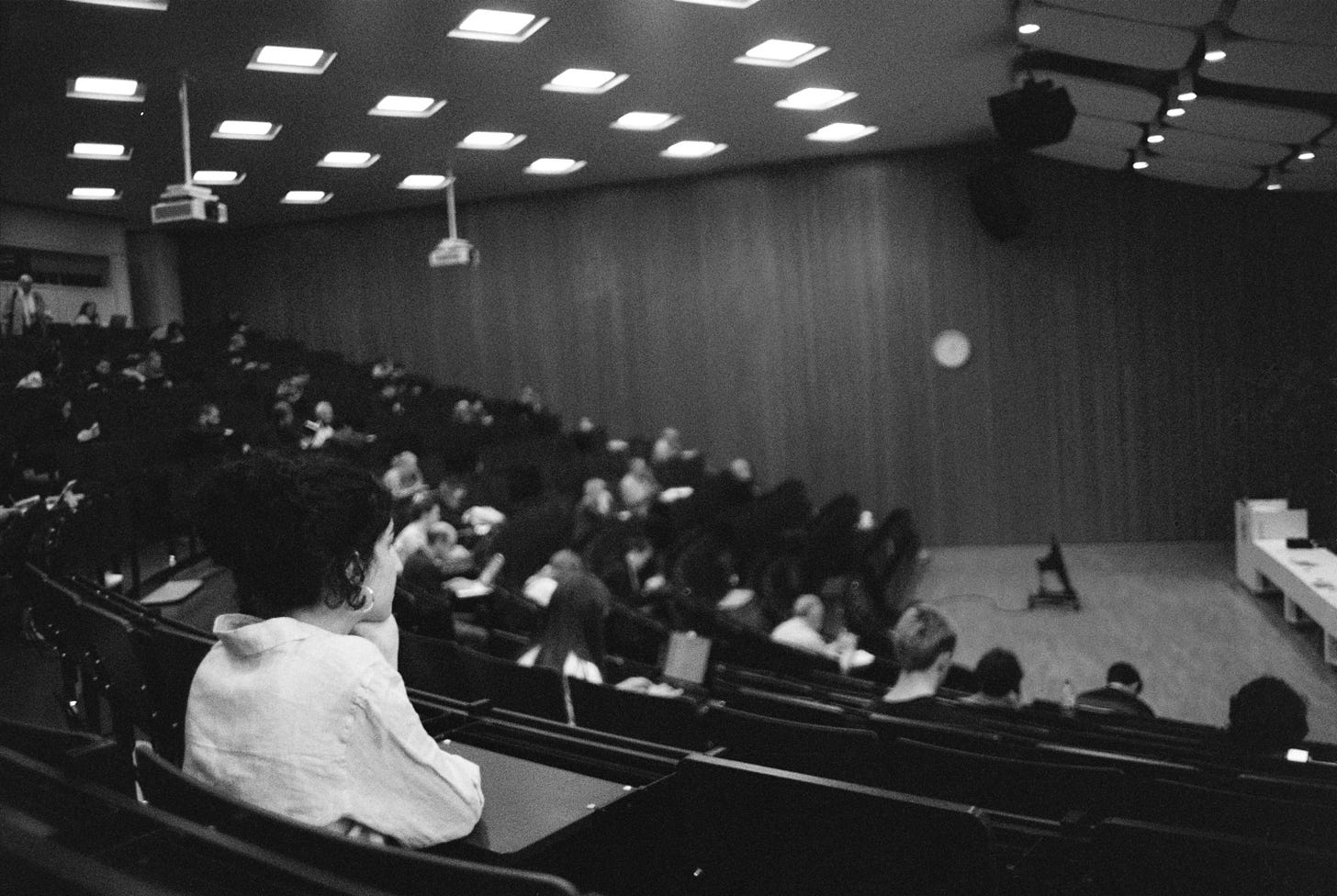 People attend a lecture in a large auditorium. People attend a lecture in a large auditorium.