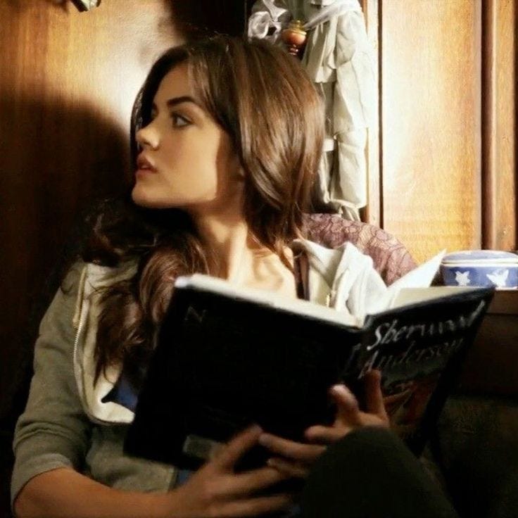 This may contain: a woman reading a book while sitting on a couch