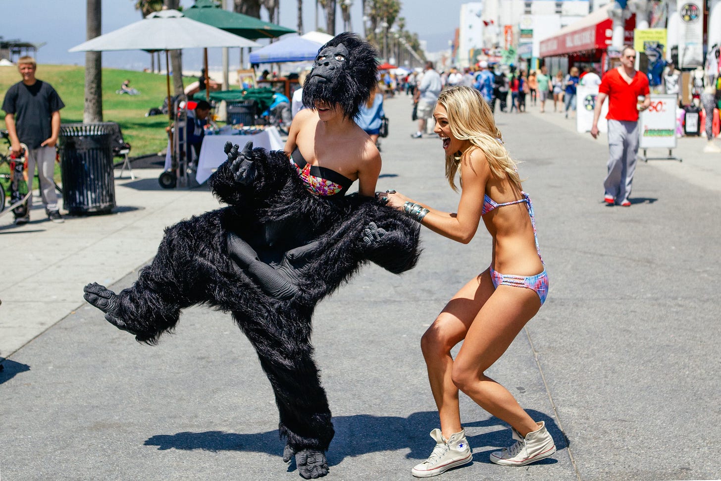 Ashley Hart pulls a gorilla costume off Barbara Palvin, revealing her in swimwear underneath.