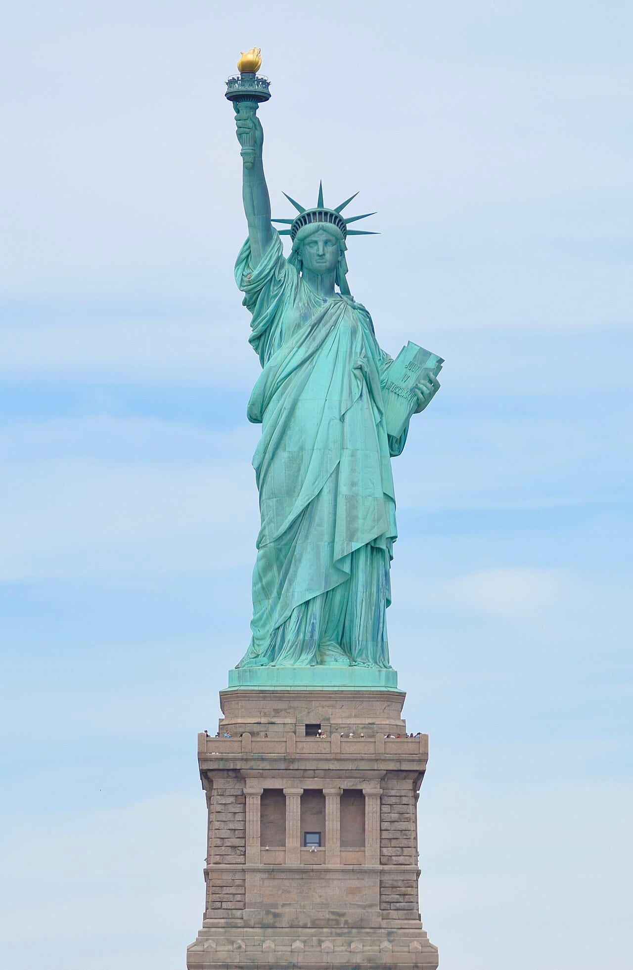 The Statue of Liberty in New York Harbor, a crowned copper figure holding up a torch, standing tall above the stone pedestal The Statue of Liberty in New York Harbor, a crowned copper figure holding up a torch, standing tall above the stone pedestal