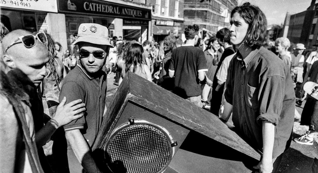 Three men carrying a large speaker on a busy street