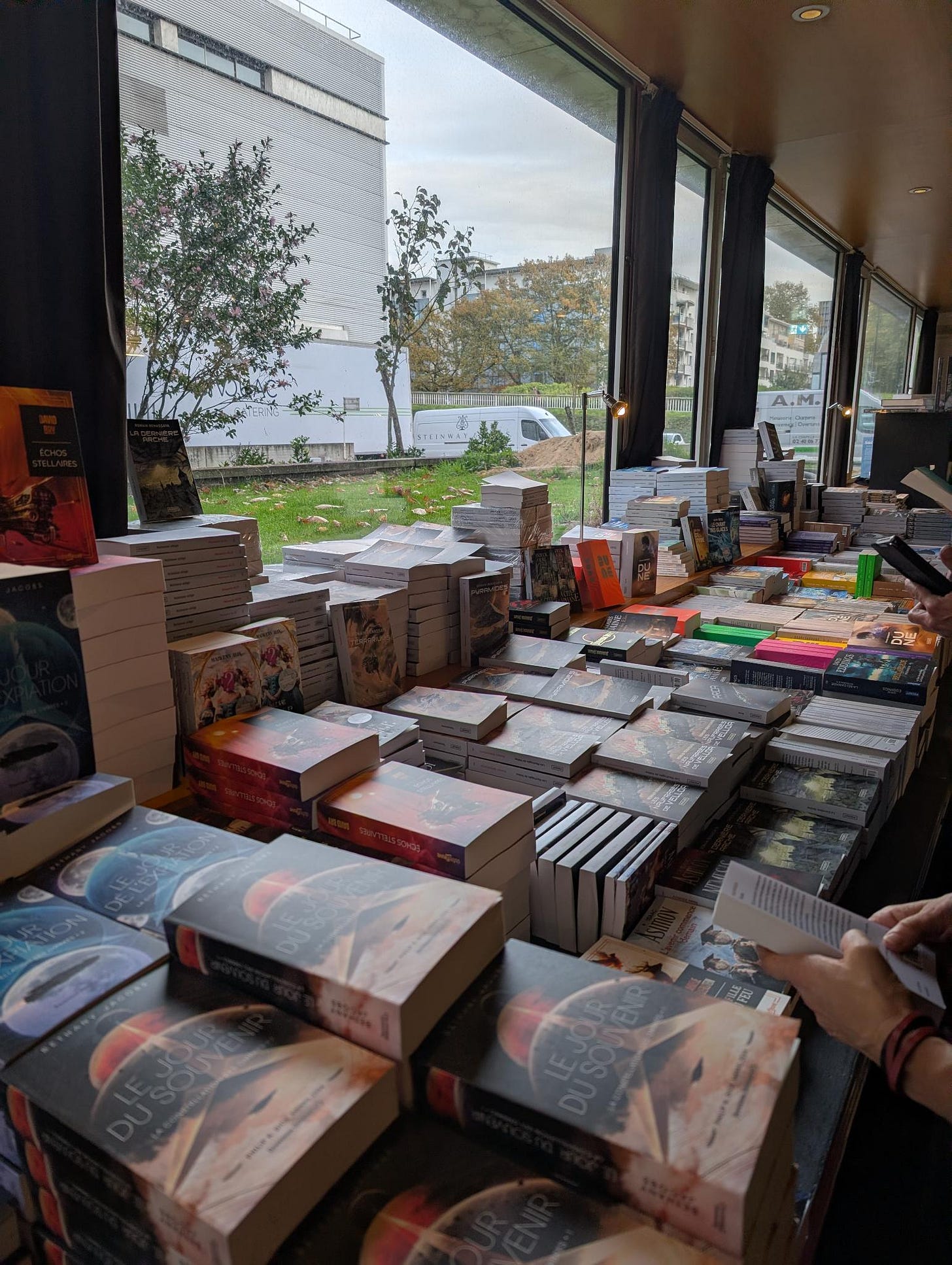 Photographie d'une longue table couverte de piles de livres. Photographie d'une longue table couverte de piles de livres.