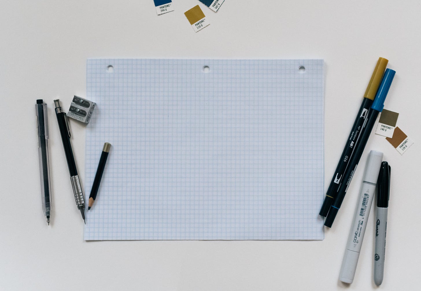 A blank piece of graph papers with pencils to the left and markers on the right