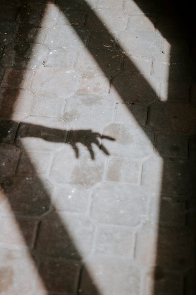 A shadowy hand against a brick floor.