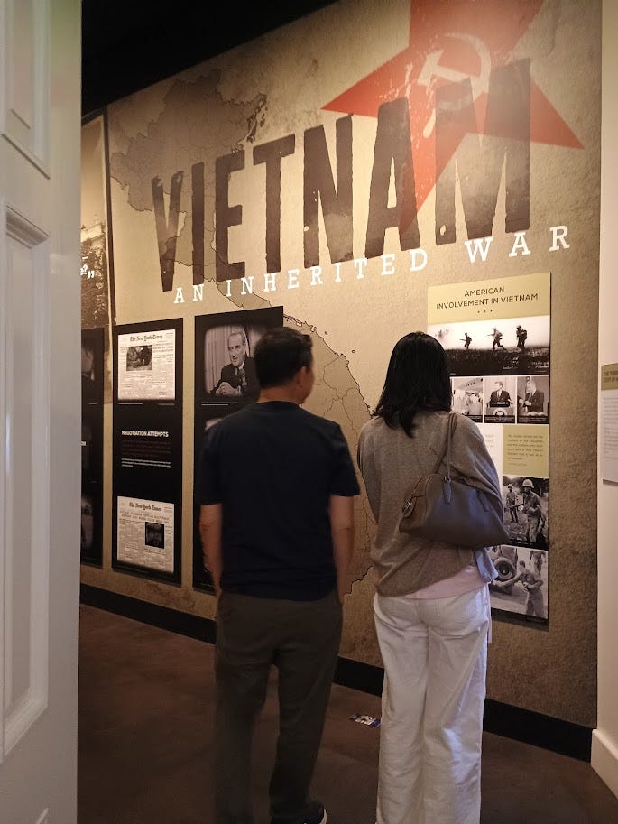 Vietnam: An Inherited War in big letters on wall, below which are photos of Lyndon Johnson, John F. Kennedy, soldiers in battle, and newspaper headlines