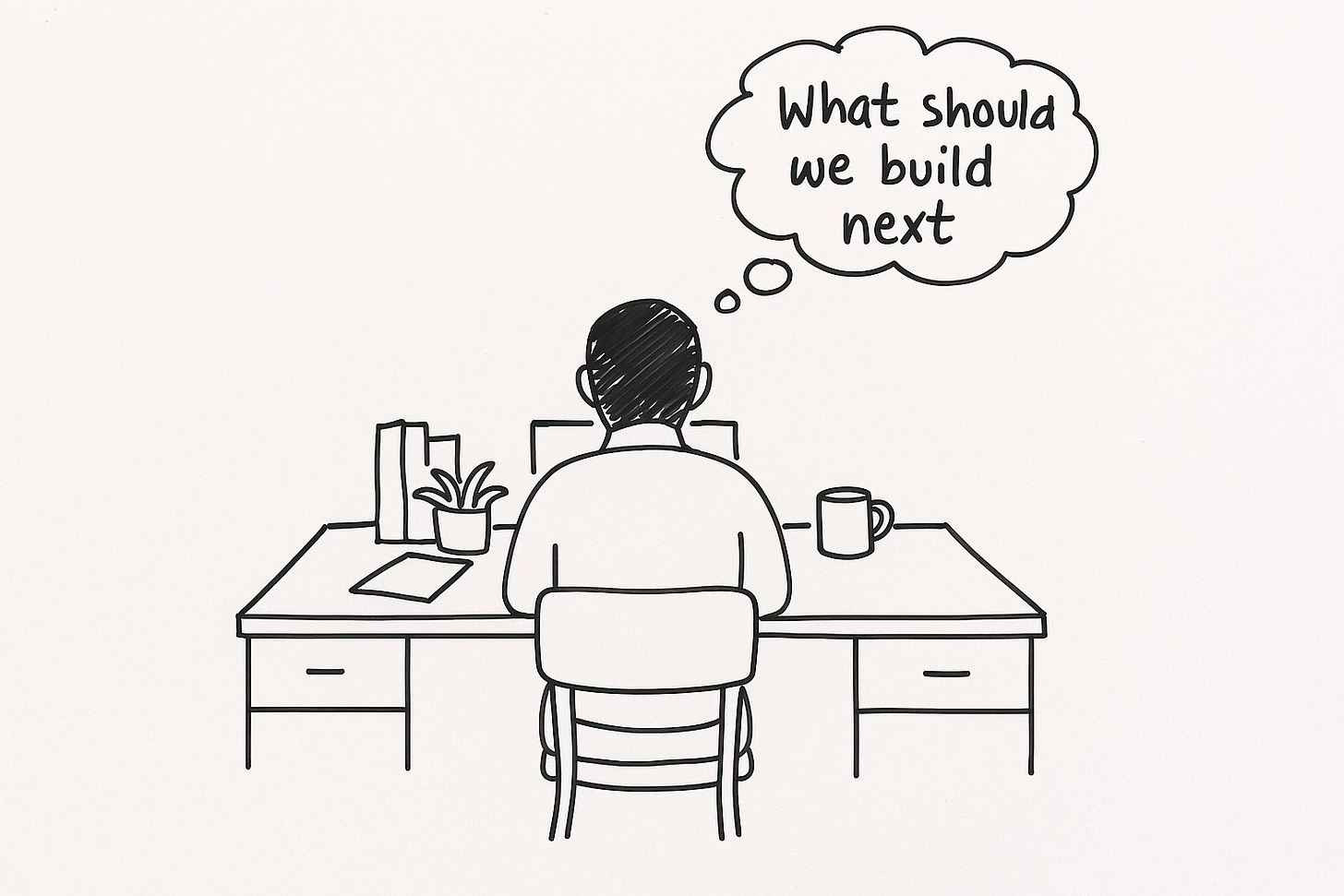 person working alone at desk natural light modern workspace laptop notebook coffee wondering "What should we build next?"