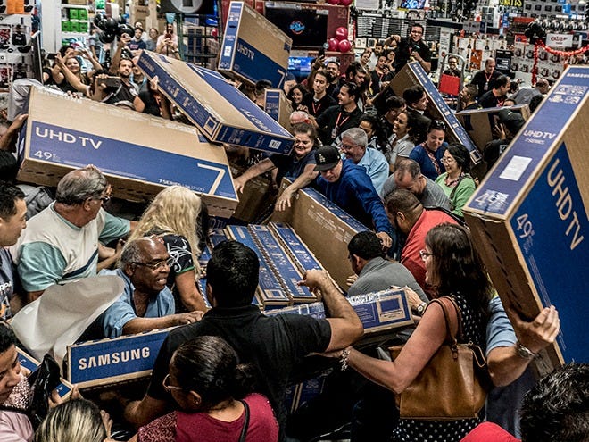 Crowd of shoppers rushing to grab discounted TVs in a busy store, illustrating market demand and consumer behavior dynamics.