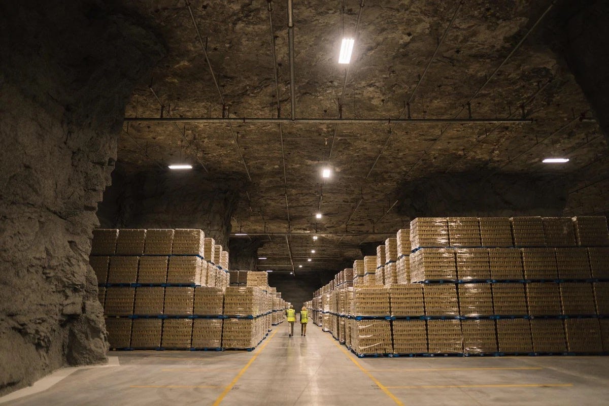 Aisle of a vast underground cheese storage cave lined with shelves of cheese. Aisle of a vast underground cheese storage cave lined with shelves of cheese.