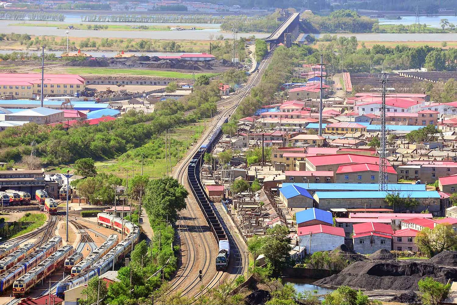 Railway bridge over river with train in foreground and railyard Railway bridge over river with train in foreground and railyard