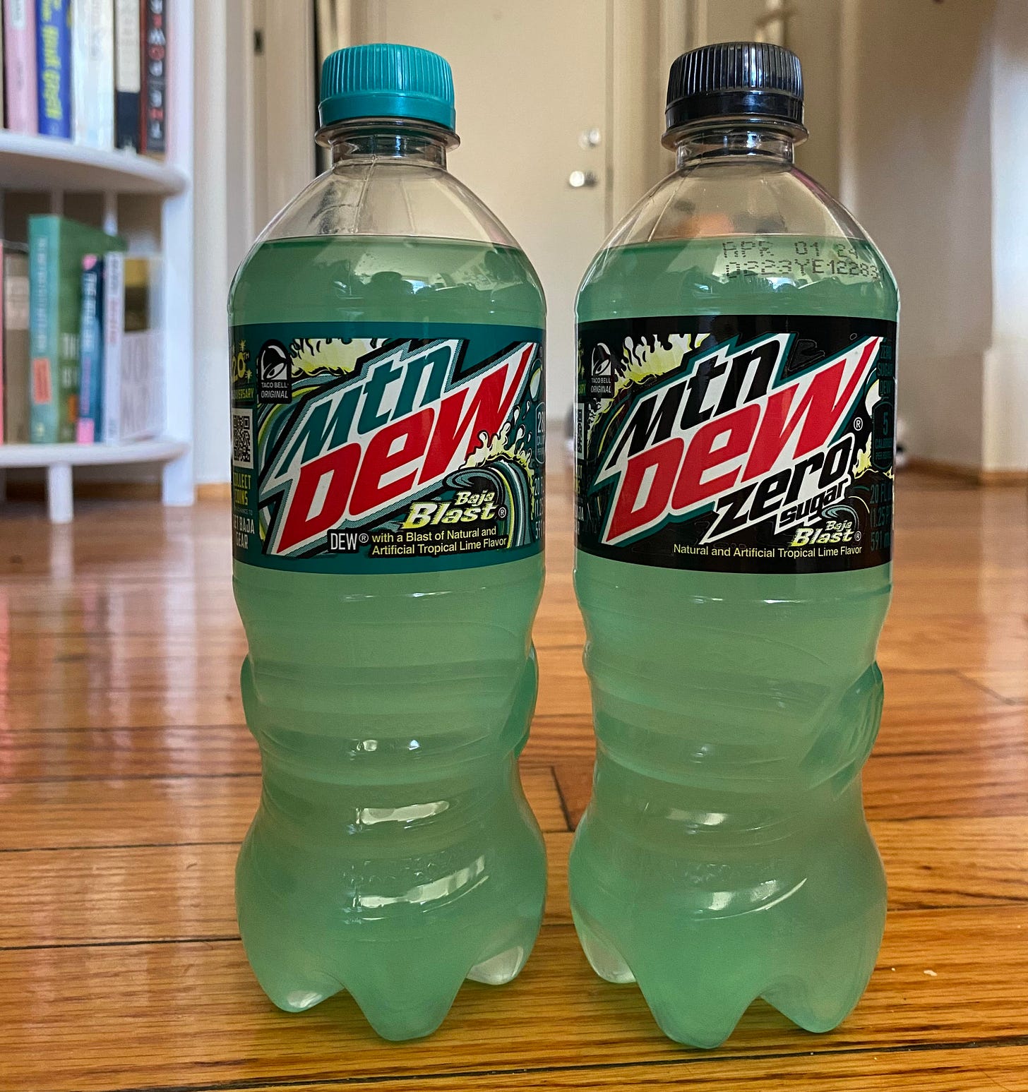 two bottles of baja blast, one regular, one zero sugar, on a hardwood floor