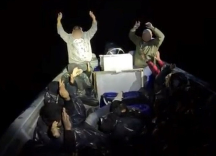 Smugglers and migrants surrender to a US Coast Guard vessel that lit up their boar with a spotlight off the Southern California coast.
