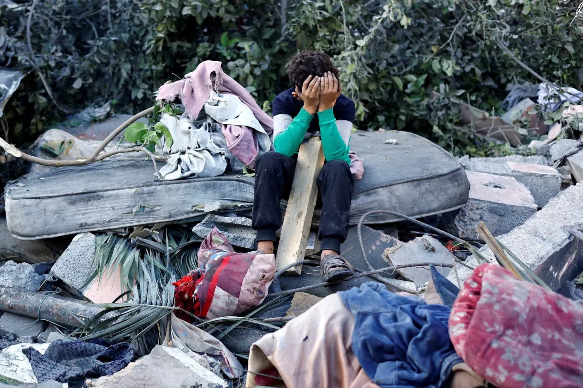 A Palestinian boy sitting at the site of an overnight Israeli strike in Gaza, October 2025