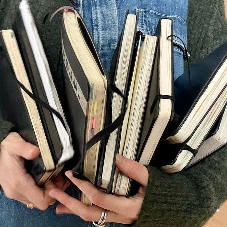 This may contain: the person is holding several books in their hands and they both have binders attached to them