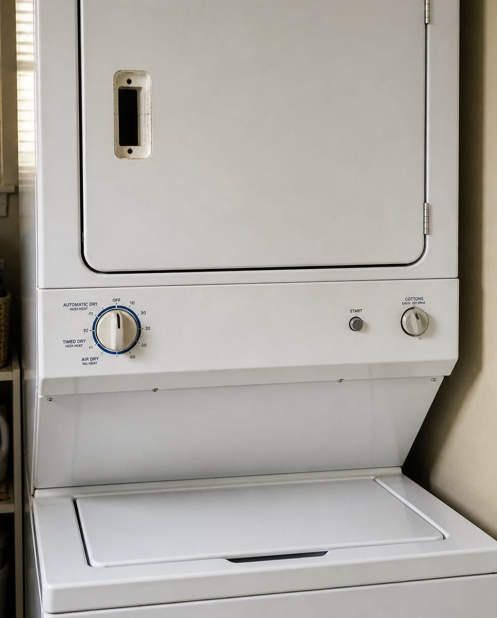 Stacked washer and dryer with dryer on top, door closed, missing handle, showing height context.