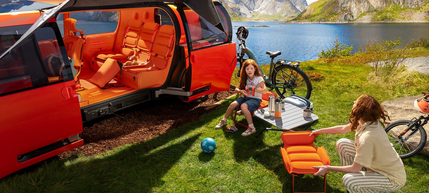 ELO parked by a lake with both side doors open, seats extracted as outdoor furniture, children playing nearby with bikes and a picnic setup. ELO parked by a lake with both side doors open, seats extracted as outdoor furniture, children playing nearby with bikes and a picnic setup.