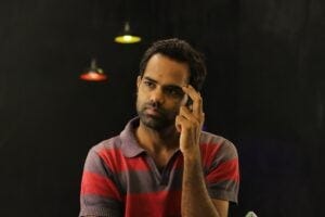 a bearded young man scratching his head